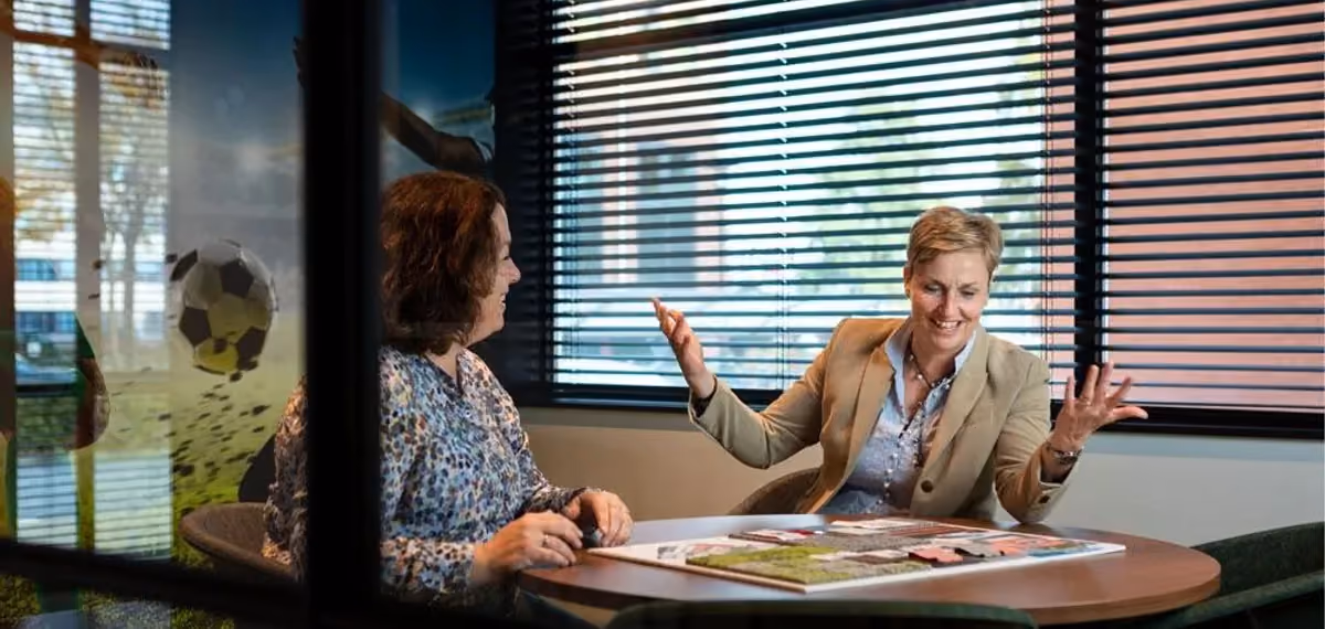 Twee vrouwen in overleg aan een vergadertafel met drukwerk