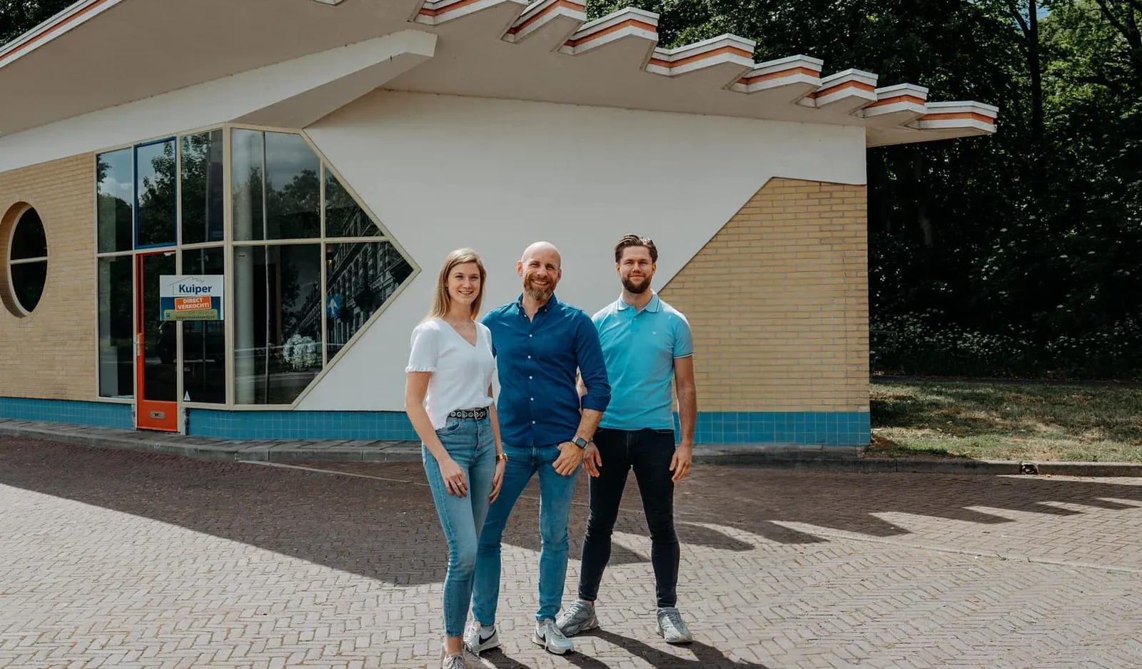 Drie medewerkers van Kuiper Makelaardij voor het kantoorpand in Arnhem