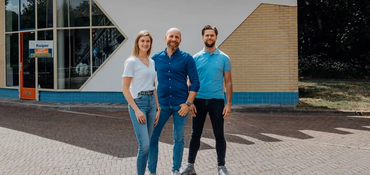 Drie medewerkers van Kuiper Makelaardij voor het kantoorpand in Arnhem