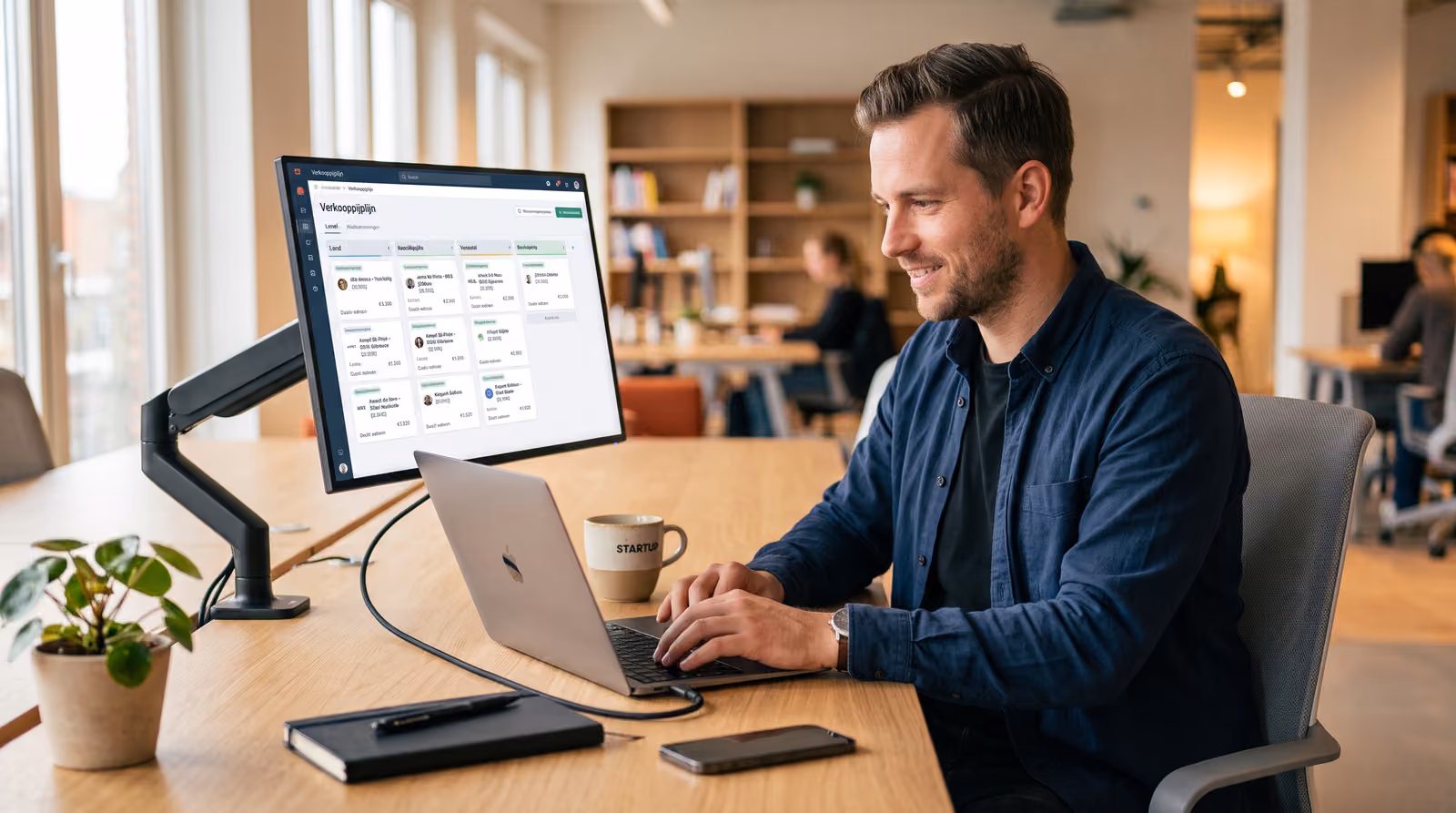 Ondernemer achter een laptop met op het scherm een klantendashboard met contactkaarten en een verkooppijplijn in blauwtinten